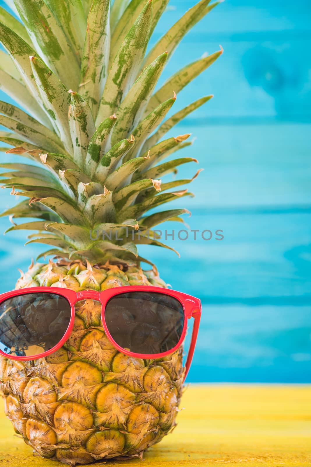 Holiday pineapple have sunglasses on blue wooden background by Sorapop