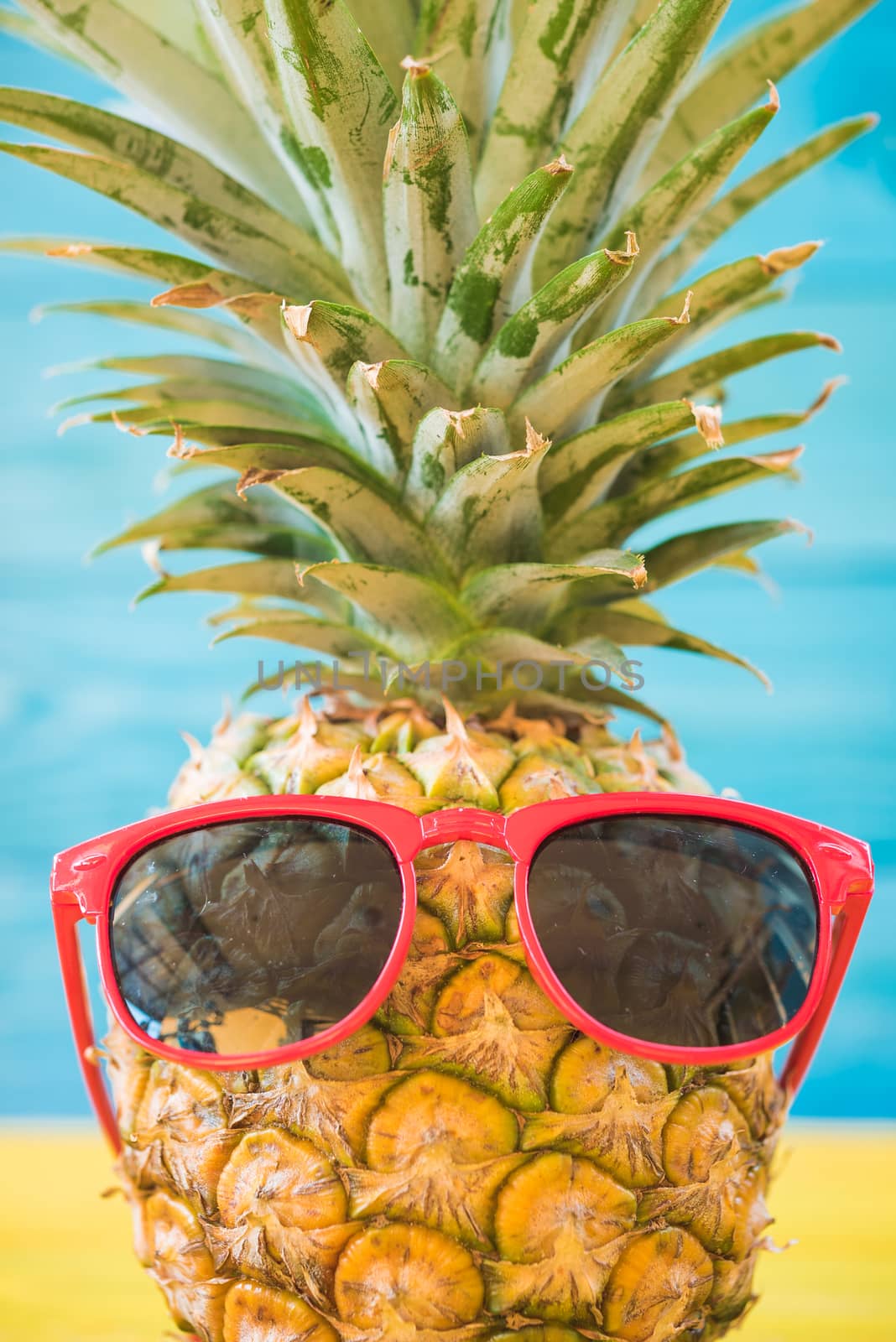 Holiday pineapple have sunglasses on blue wooden background, tropical holiday concept