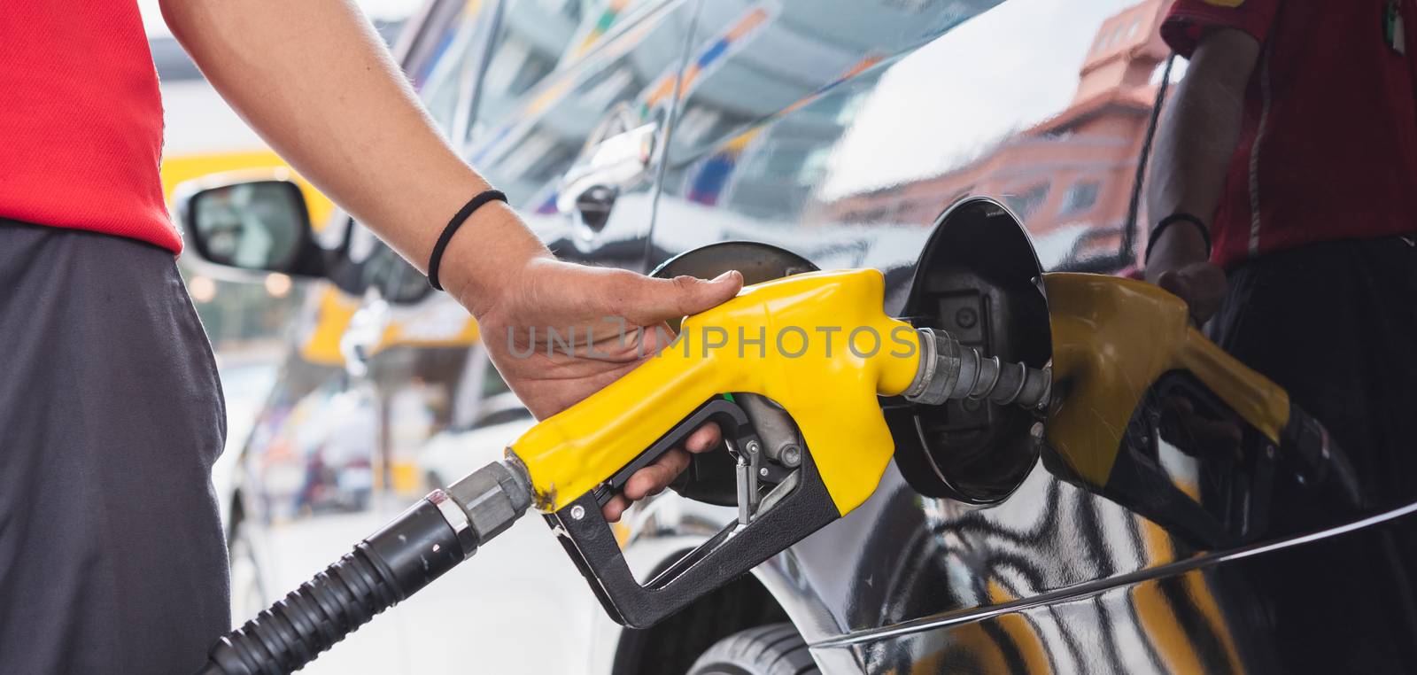 Staff in uniform hand holding gun refueling gasoline vehicle car at gas filling station