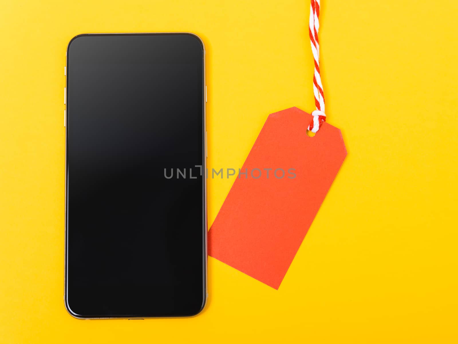 Blank red tag label shopping concept and smart phone blank screen, with copy space on yellow background