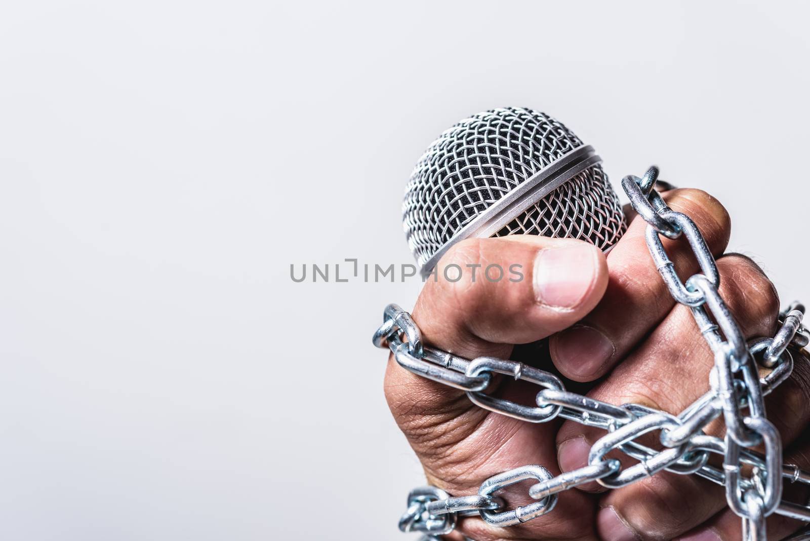 Hand holding microphone and have chain on fist hand by Sorapop