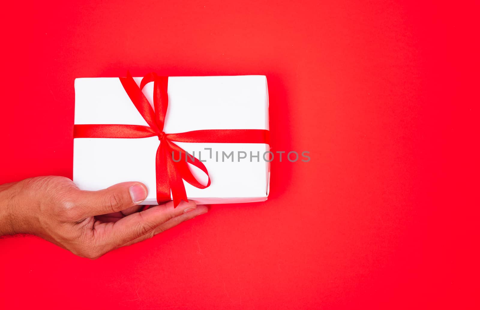 Happy New Year and Christmas 2020 or valentine day, top view hands with white gift box on red background with copy space for your text