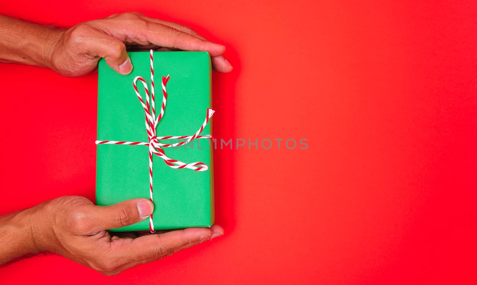 Happy New Year and Christmas 2020 or valentine day, top view hands with green gift box on red background with copy space for your text