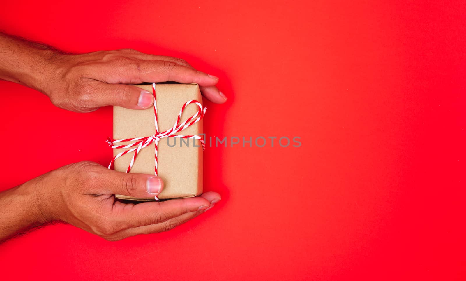 Happy New Year and Christmas 2020 or valentine day, top view hands with Brown gift box on red background with copy space for your text