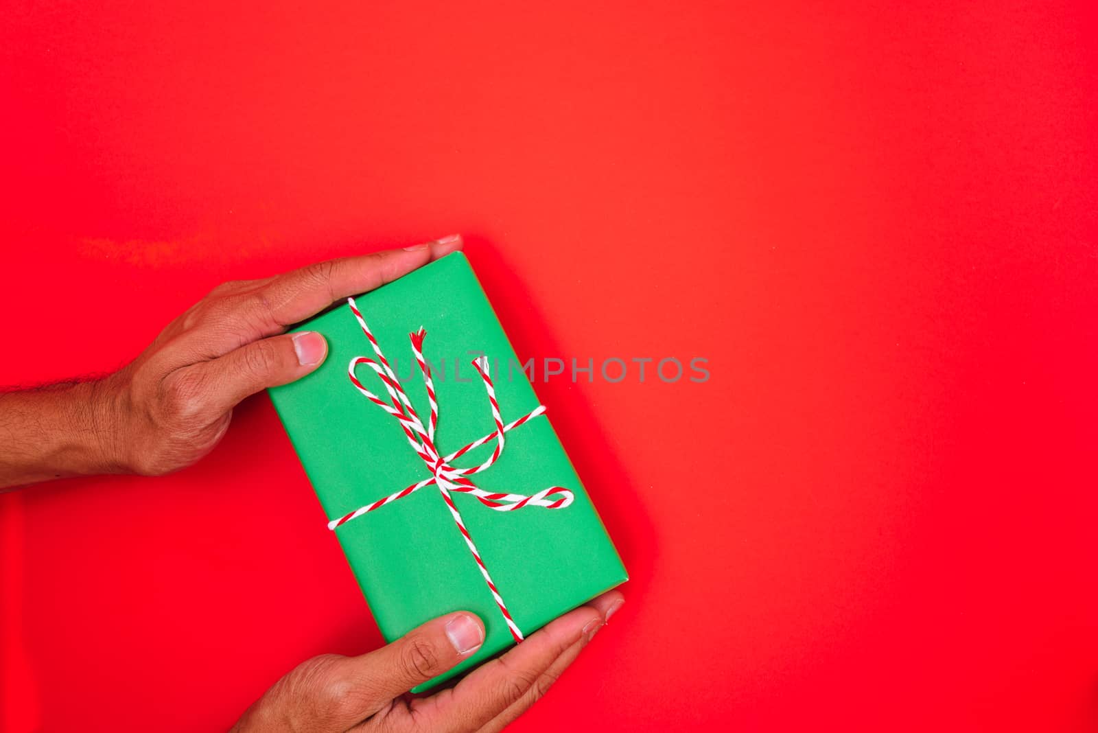 Happy New Year and Christmas 2020 or valentine day, top view hands with green gift box on red background with copy space for your text