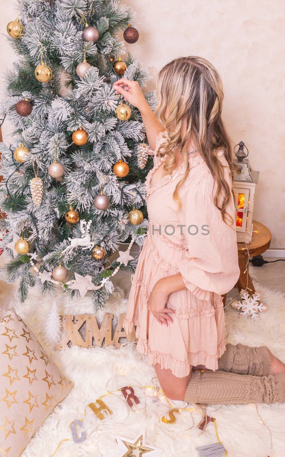A woman decorates the Christmas tree with festive Christmas ornaments