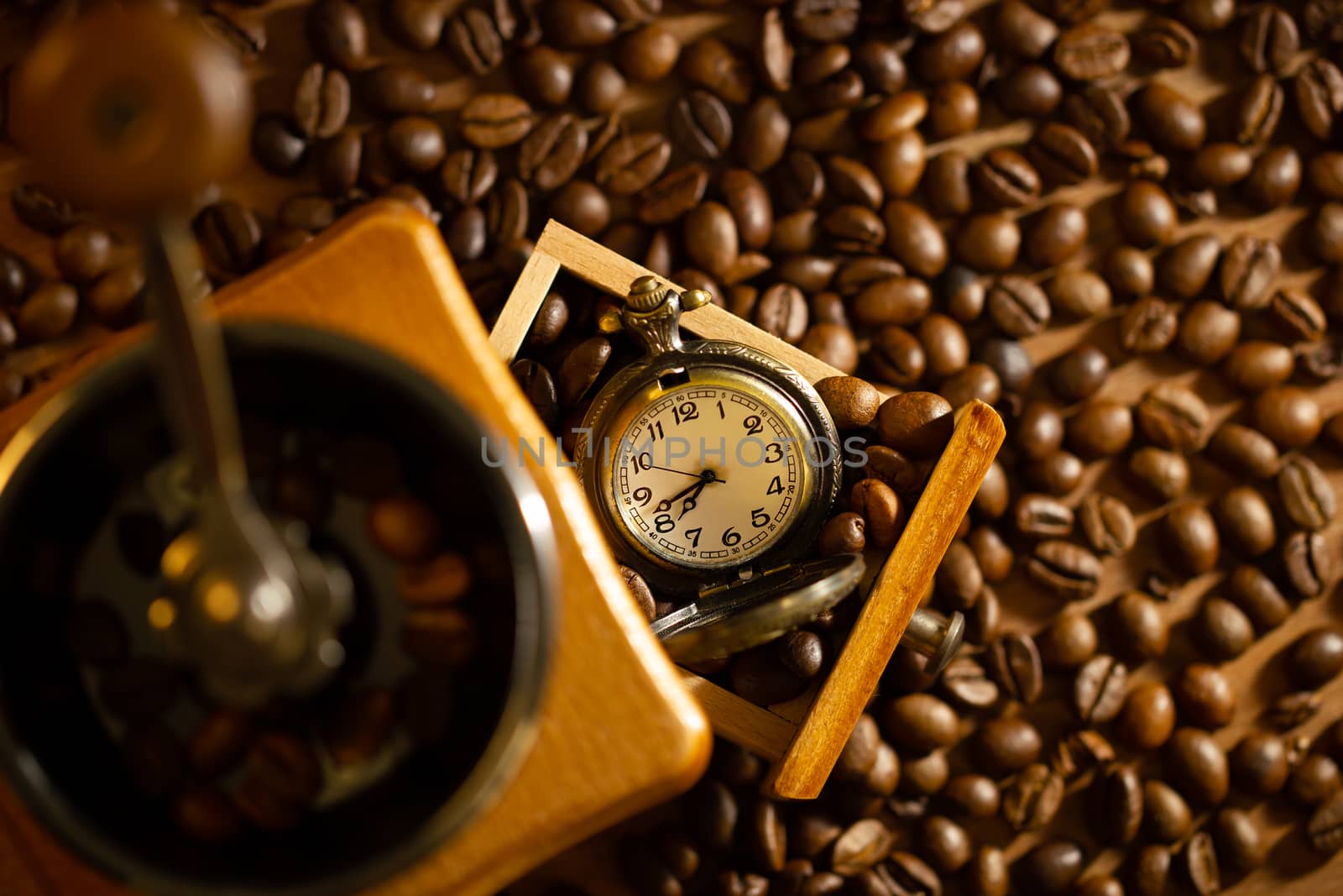 Coffee bean and pocket watch the tray of manual grinder on table by SaitanSainam