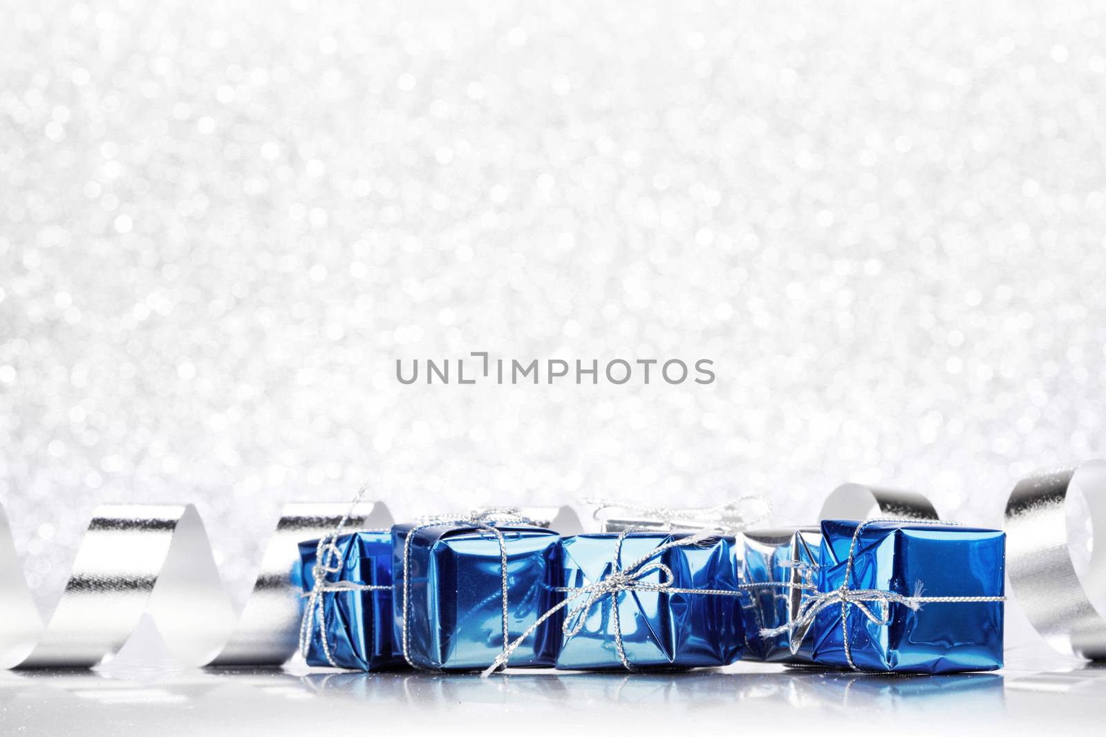Decorative blue boxes with holiday gifts on shiny glitter background