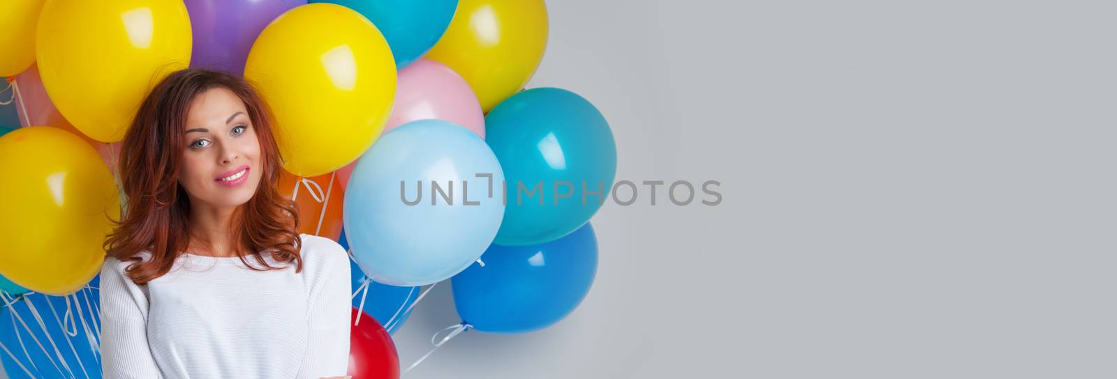 Young pretty woman in white with colored balloons on white background with copy space for text