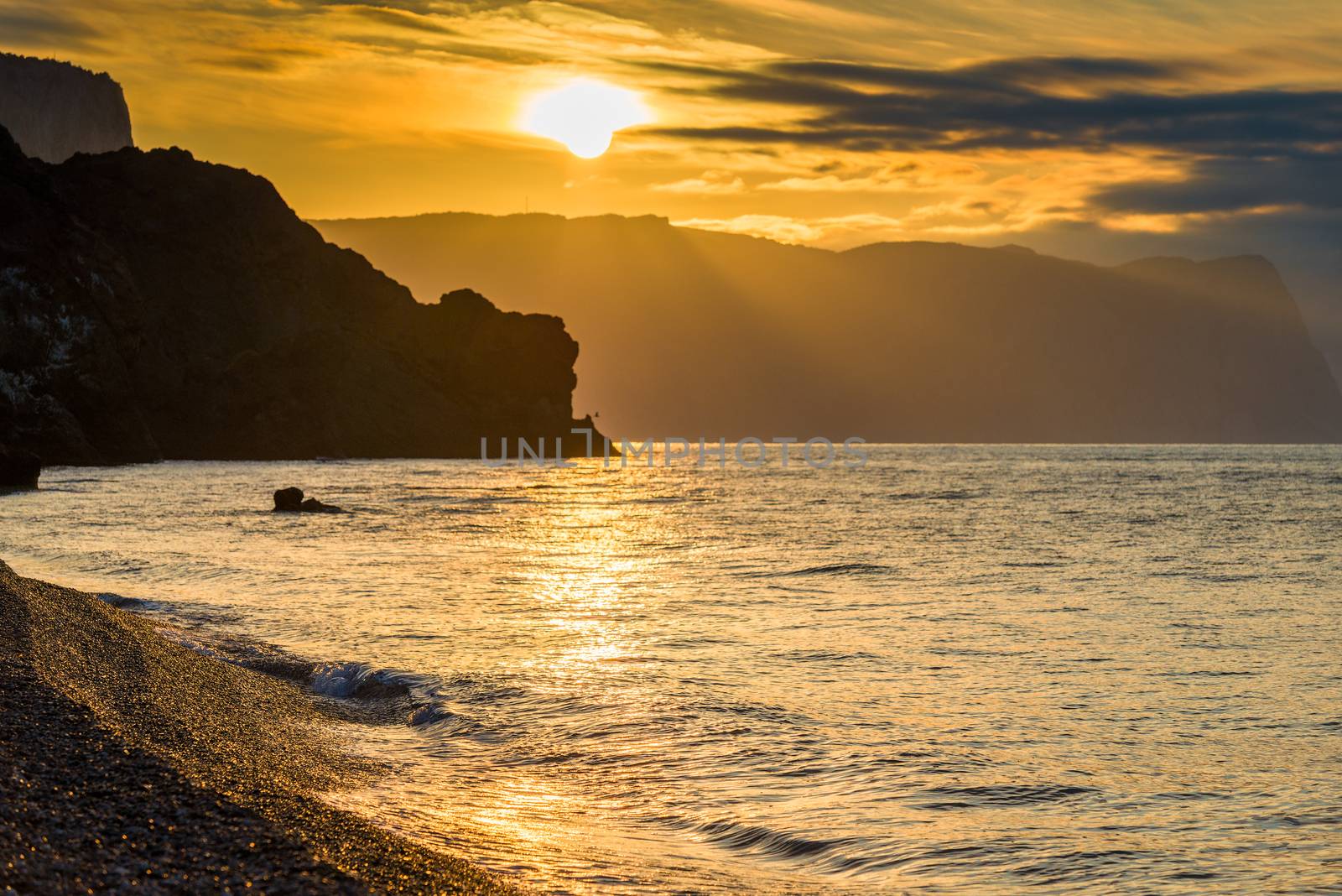 The Black Sea in the rays of the rising sun, a view of the water and rocks. Orange Tone's Photo