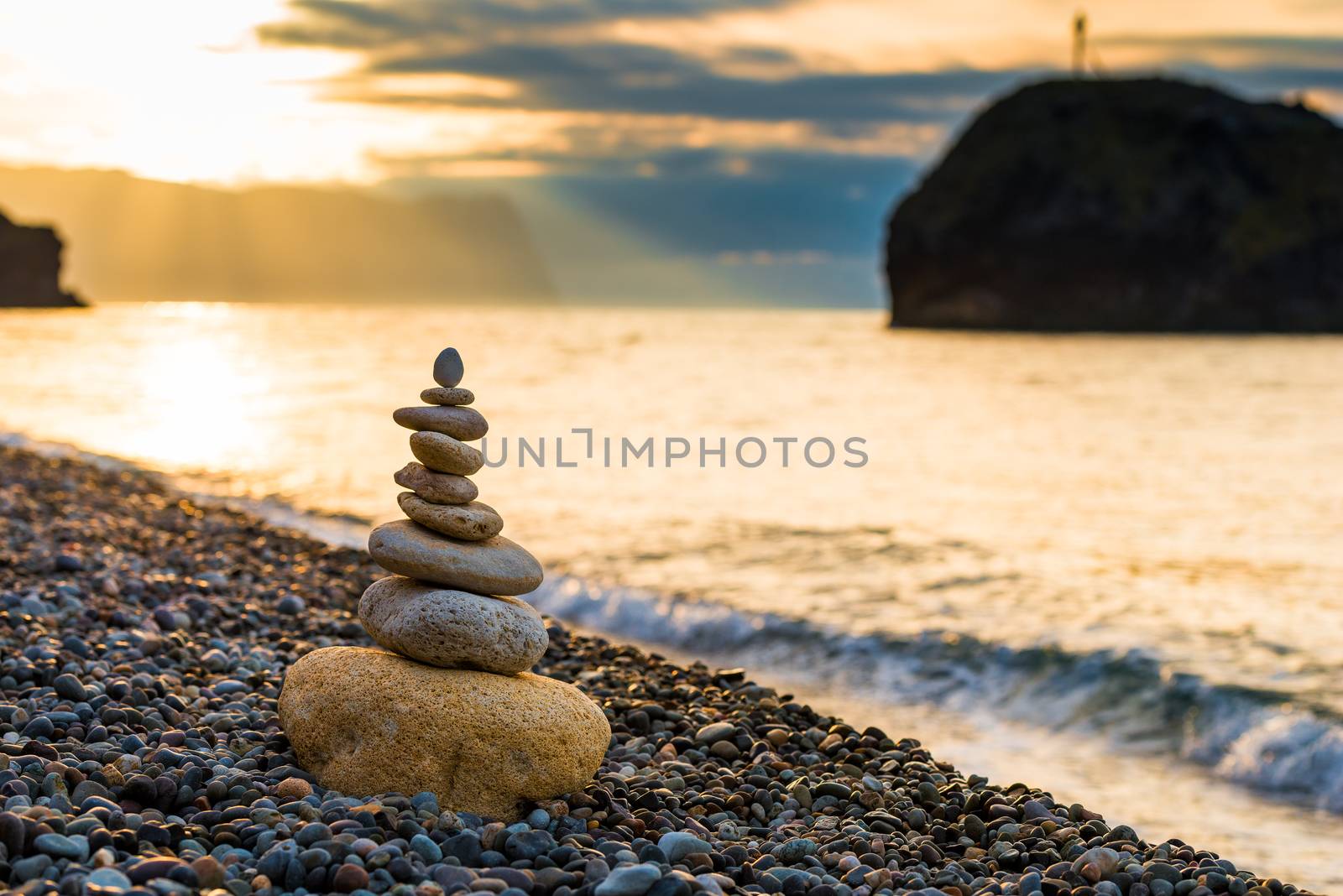 balance at dawn - close-up of a pyramid of white stones on a peb by kosmsos111