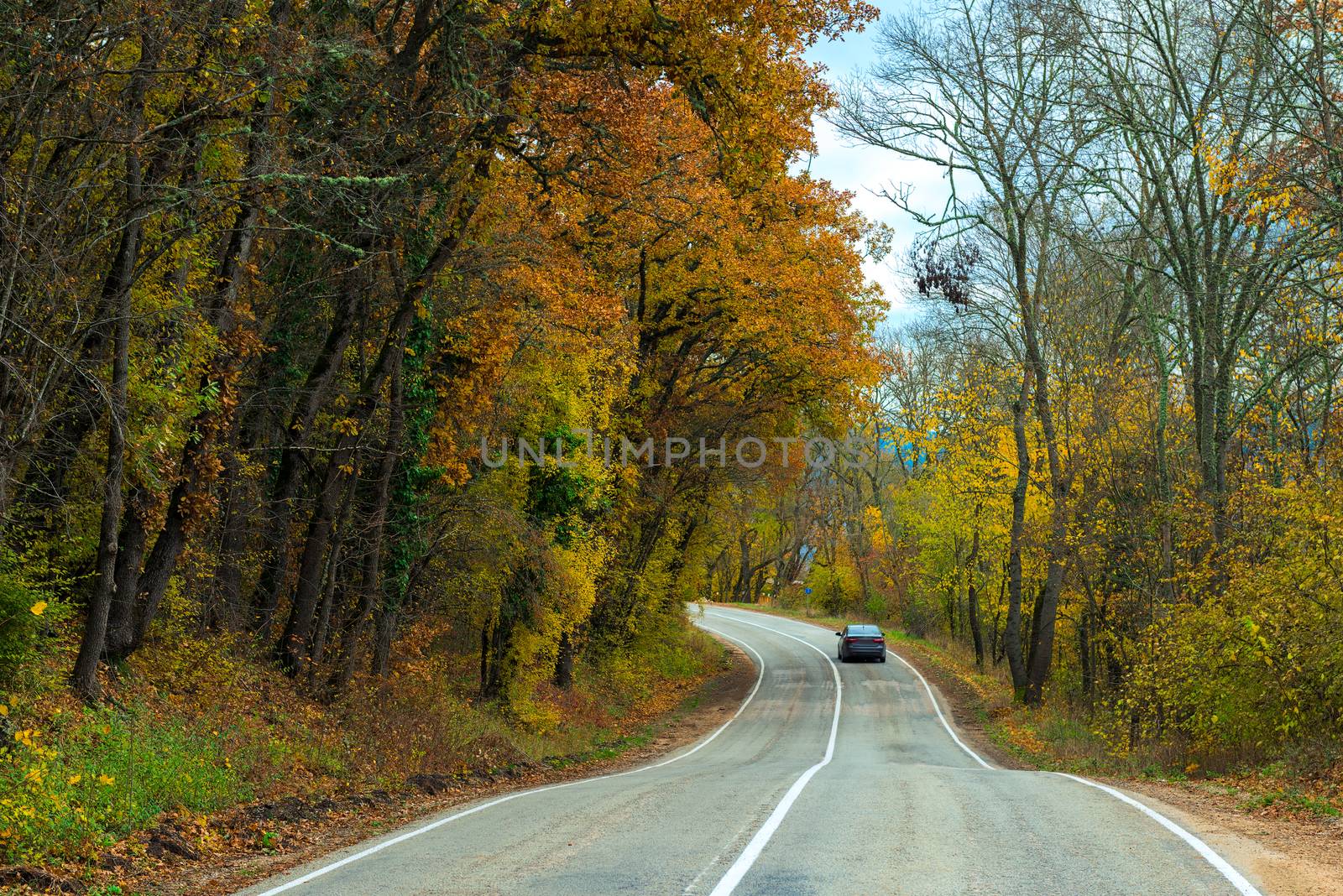 Car moving along a winding road in the mountains on an autumn afternoon