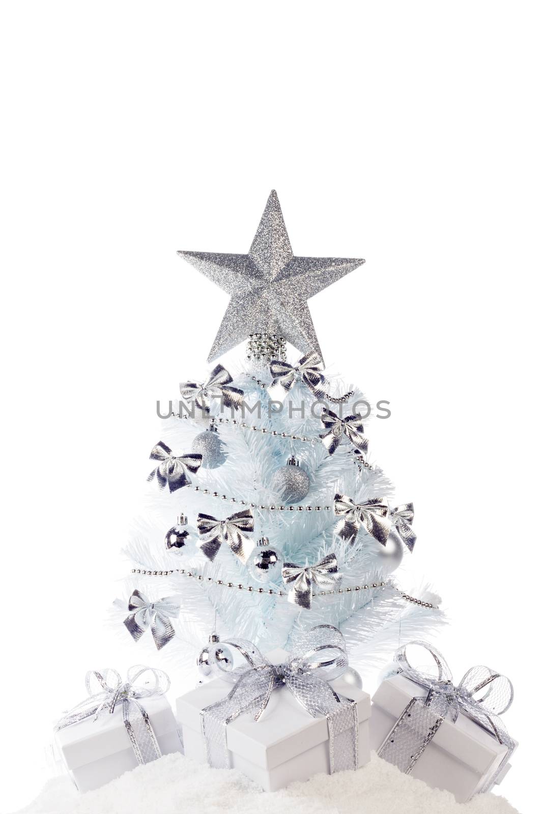 White christmas tree with silver decorations and gifts on snow isolated on white background