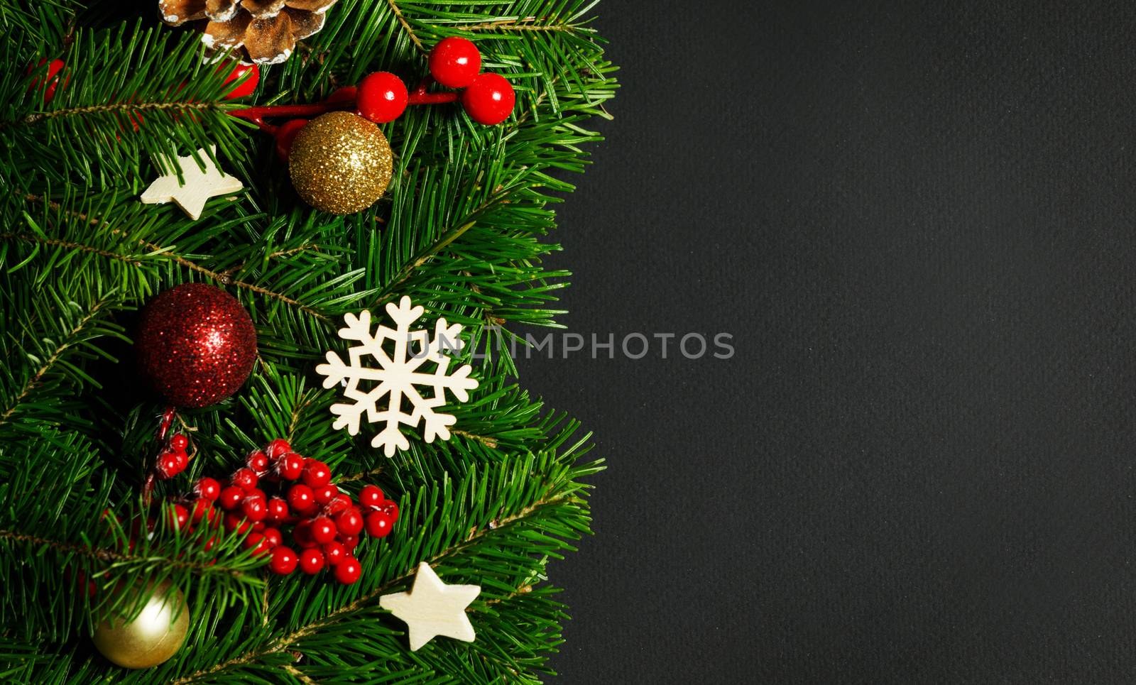Natural fir Christmas tree border frame with decor on black, copy space for text