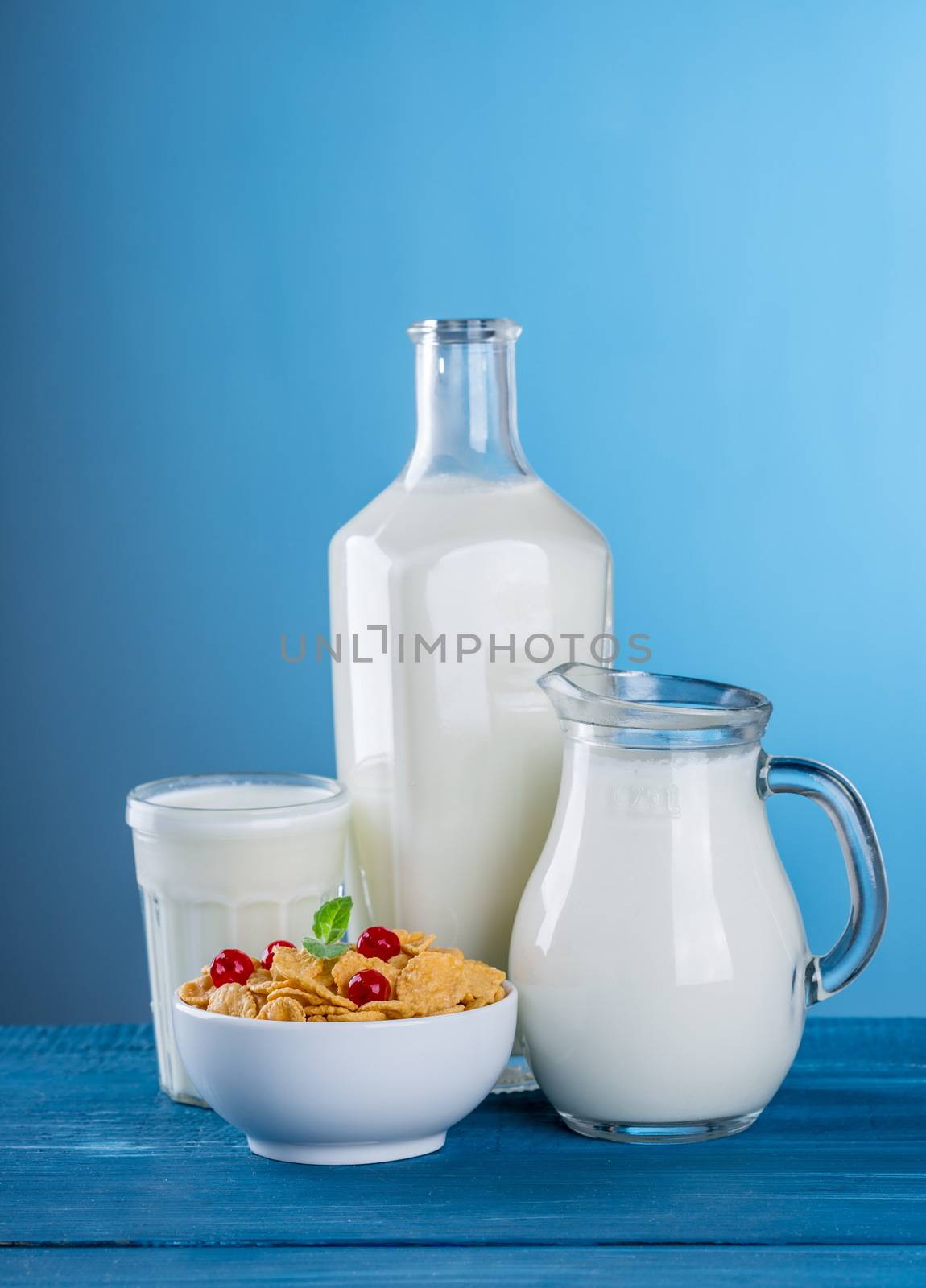 In images A glass of milk and a milk jug on plaid tablecloth.