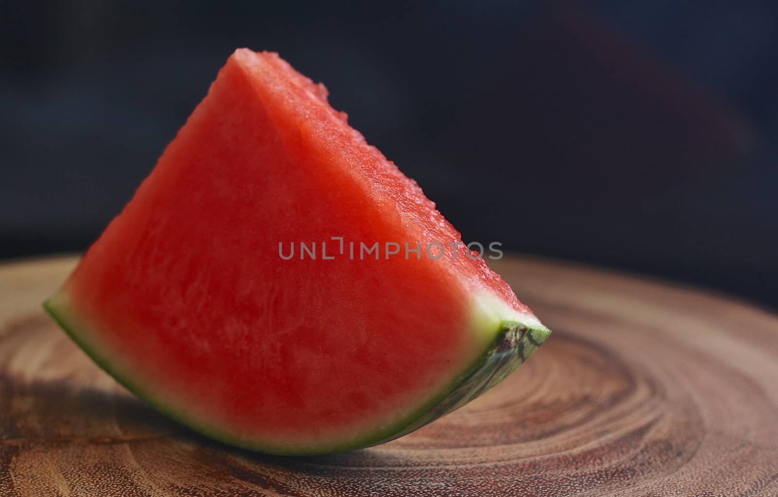 In images watermelon and watermelon pieces in a wooden background.