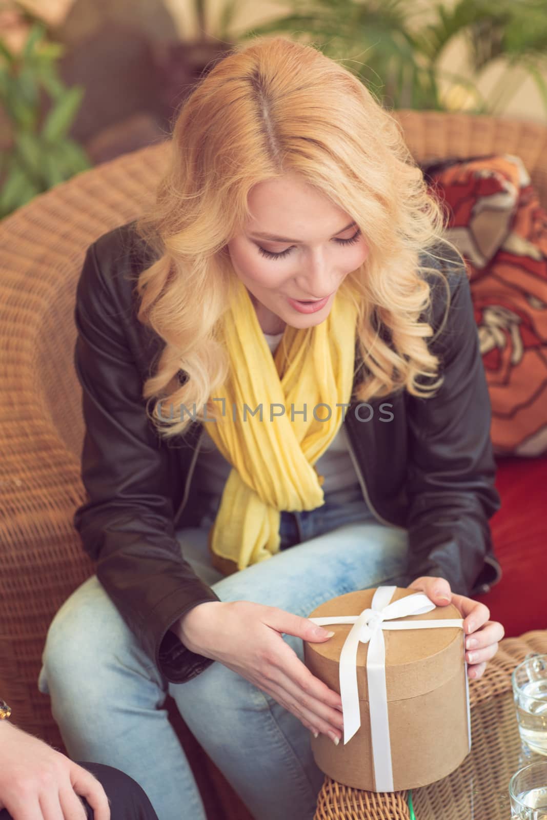 Surprised woman sitting by the table in cafe and getting a gift. Dating , Valentines day concept