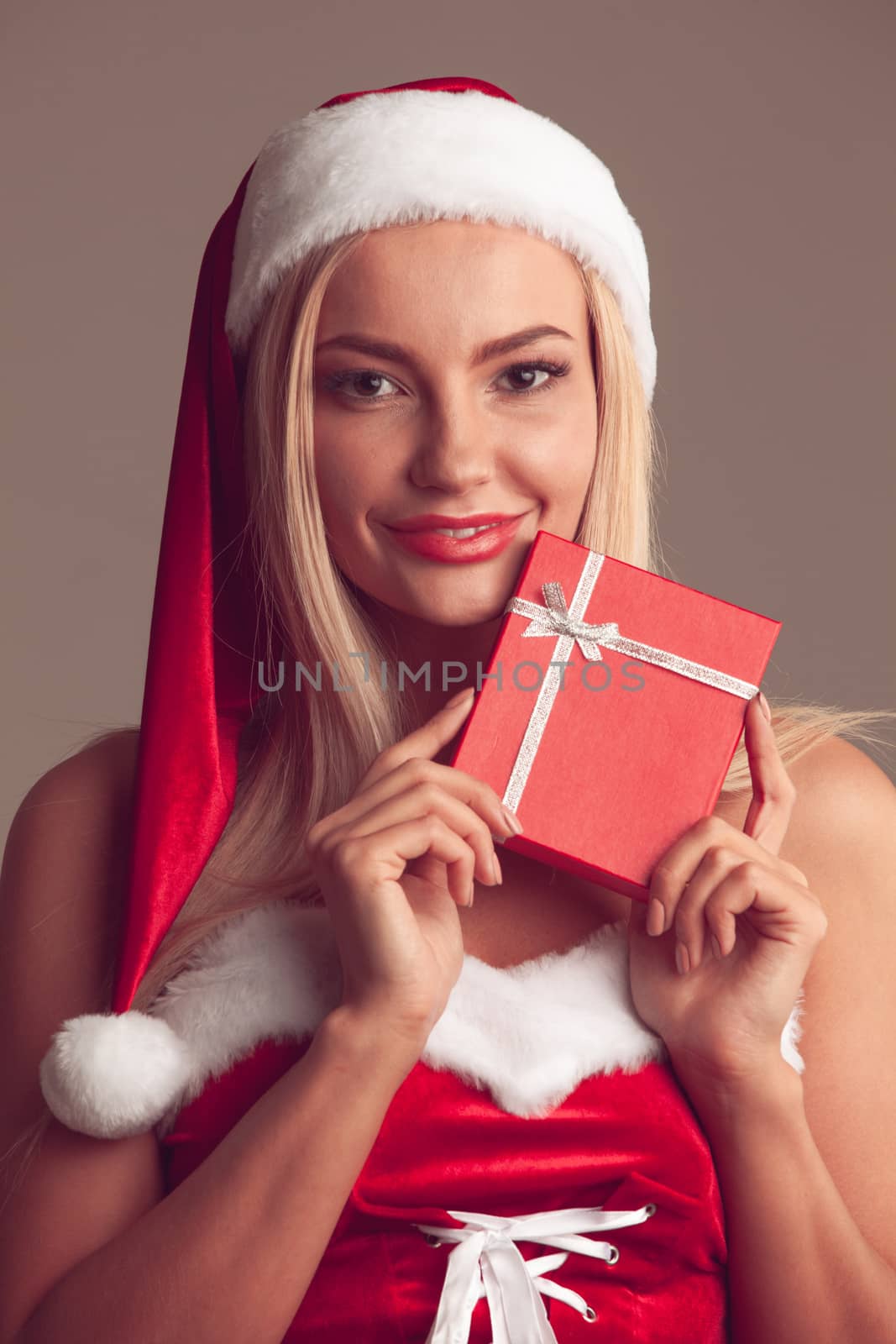 Happy excited young woman in santa dress and hat with gift box toned image
