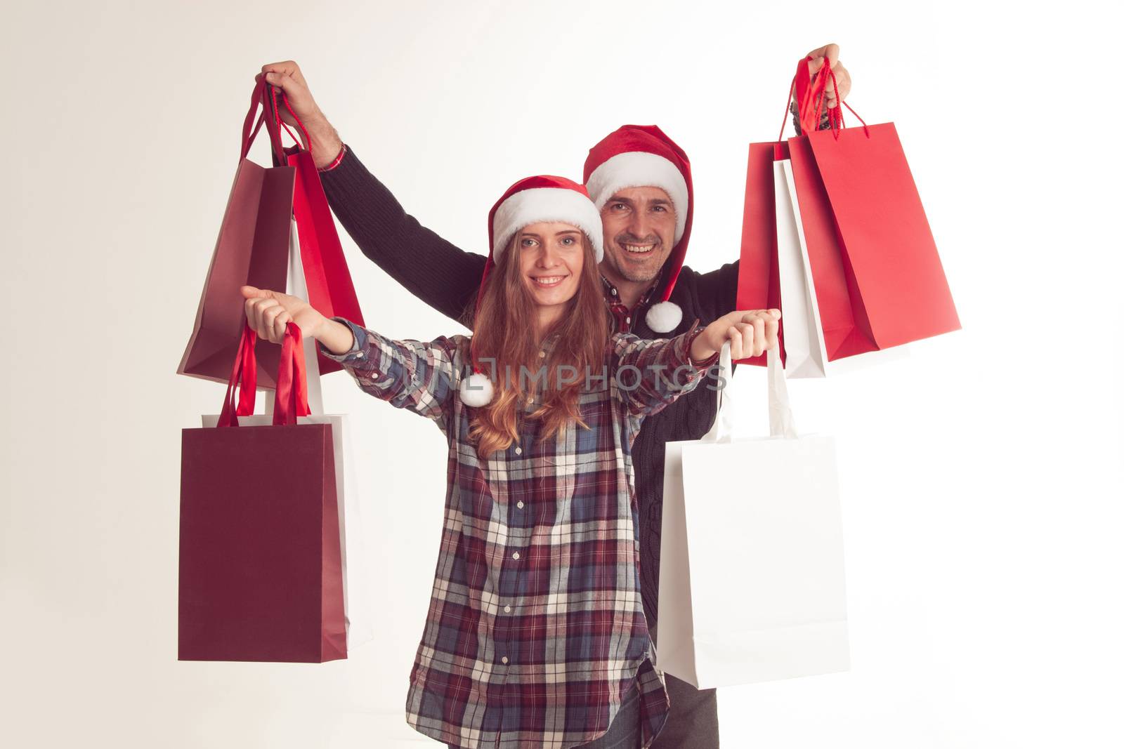 Happy couple holding shopping bags of Christmas presents on white background