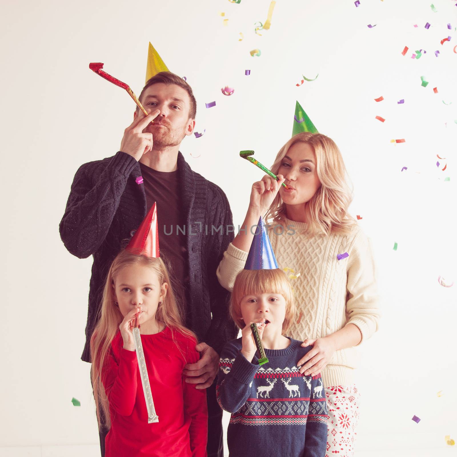 Family blowing party trumpets with confetti celebrating new year