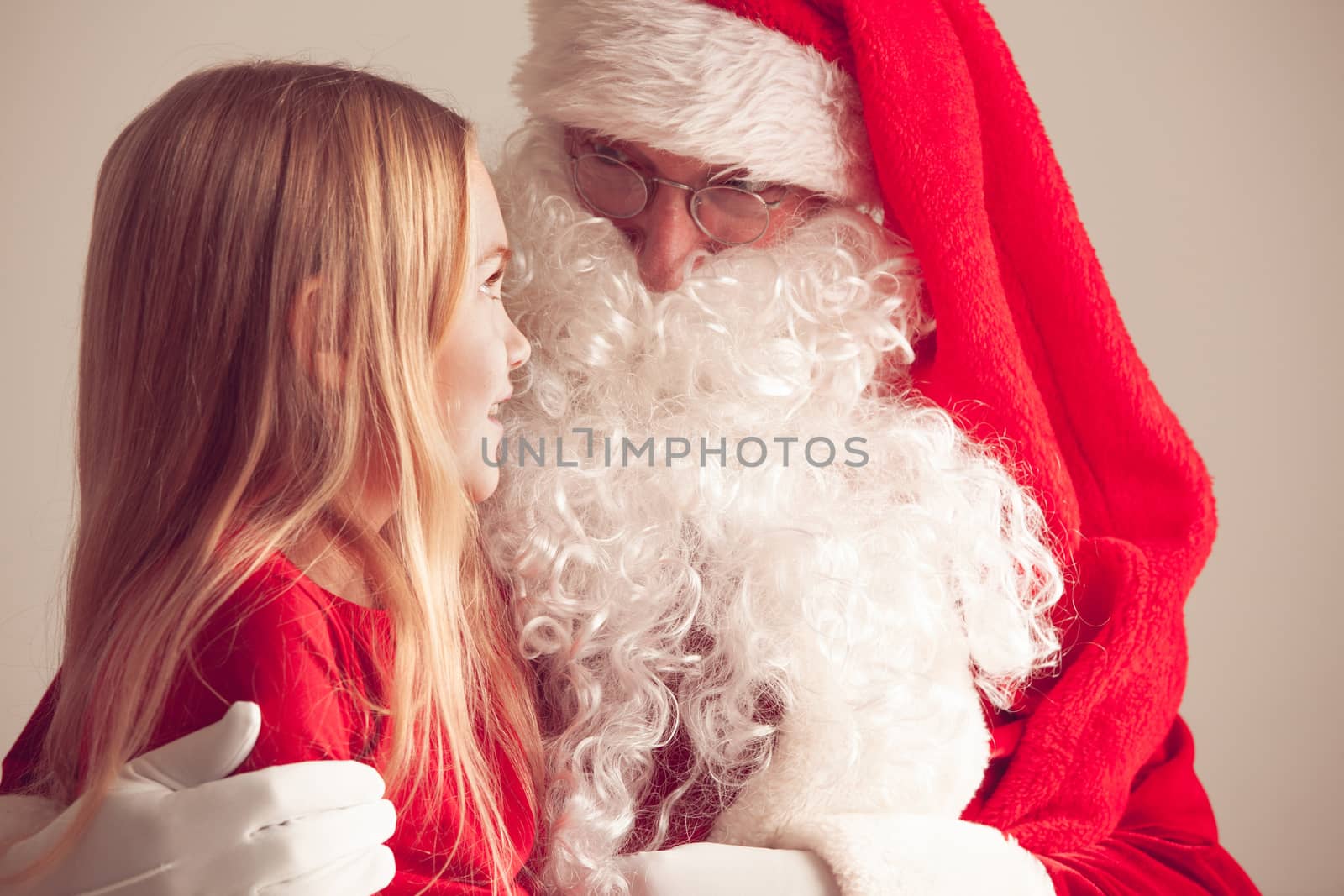 Portrait of smiling little girl sitting on santa claus knees