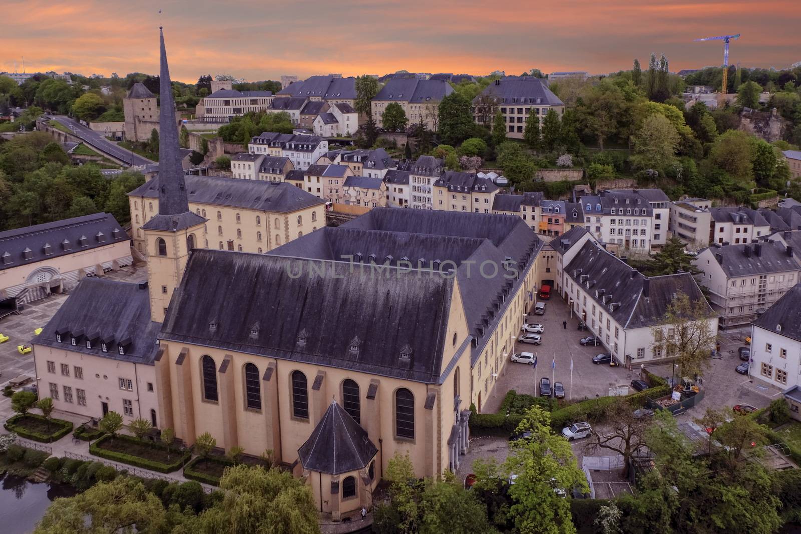Alzette river, church of St Jean du Grund and Abbey de Neumunster in Old Town Luxembourg City from top view by sunset