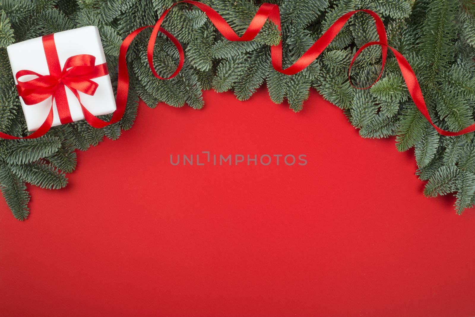 Christmas fir tree branches and decorated gift box border frame on red background with copy space for text