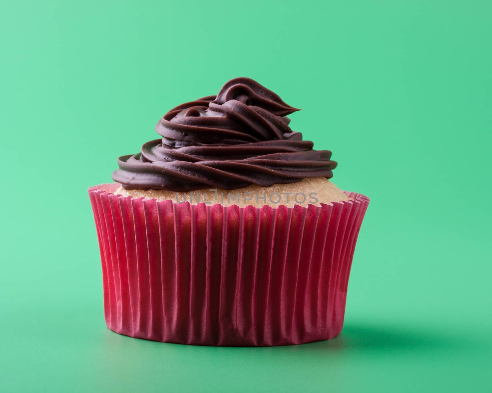 Delicious vanilla cupcake with chocolate icing, green background by lanalanglois