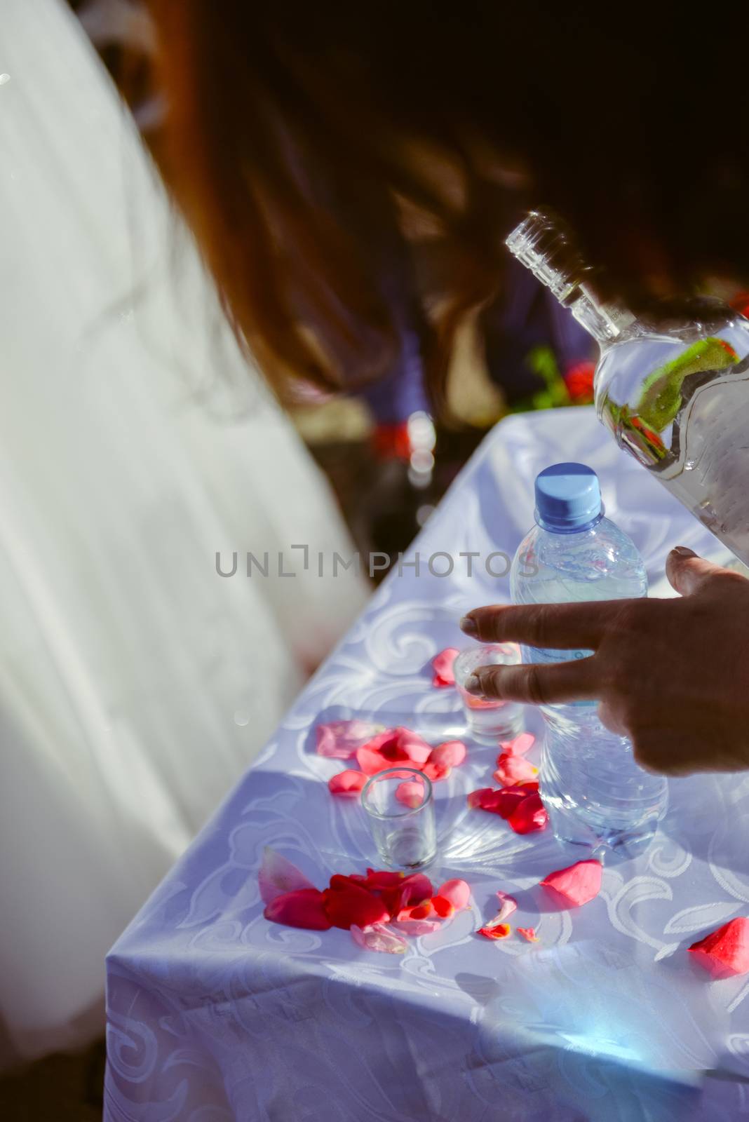 Bottle of cold vodka and wine bottle in bucket with ice and orange juice in jug on table, copy space. Alcohol bottles in ice bucket in restaurant. Wedding party