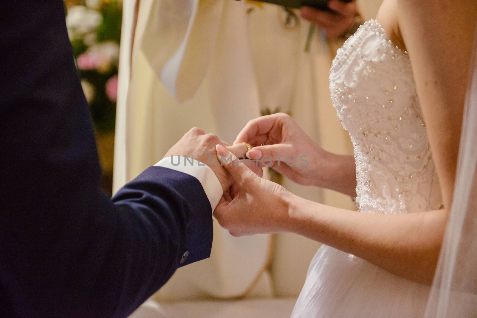 the bride and groom during the wedding ceremony put wedding rings on their fingers.