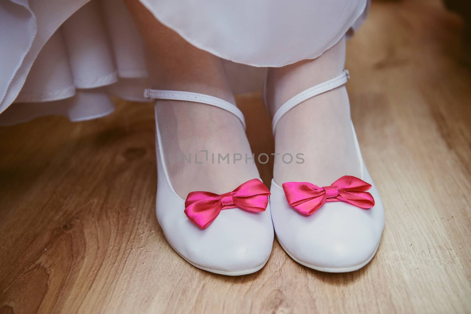 The bride shows white wedding shoes. Wedding detail. Close up