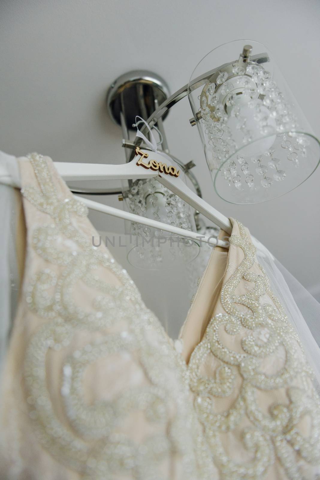 Bridesmaid helping slender bride lacing her wedding white dress, buttoning on delicate lace pattern with fluffy skirt on waist. Morning bridal preparation details newlyweds. Wedding day moments, wear.