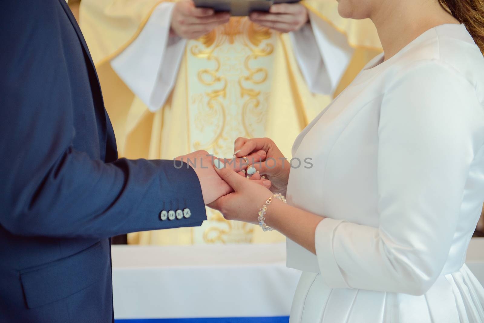 the bride and groom during the wedding ceremony put wedding rings on their fingers.