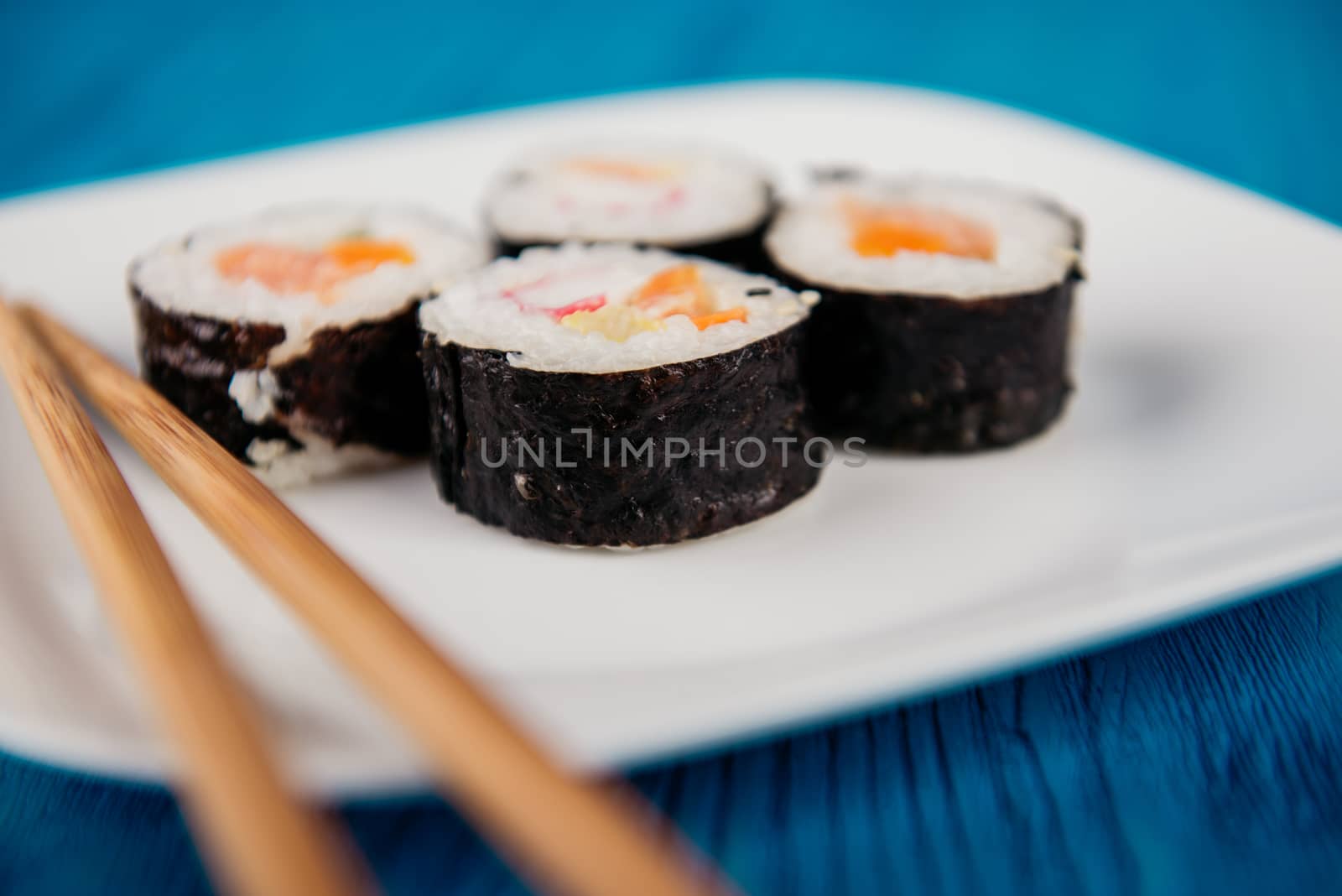 Appetizing tasty Japan rolls on a plate isolated on blue wooden background