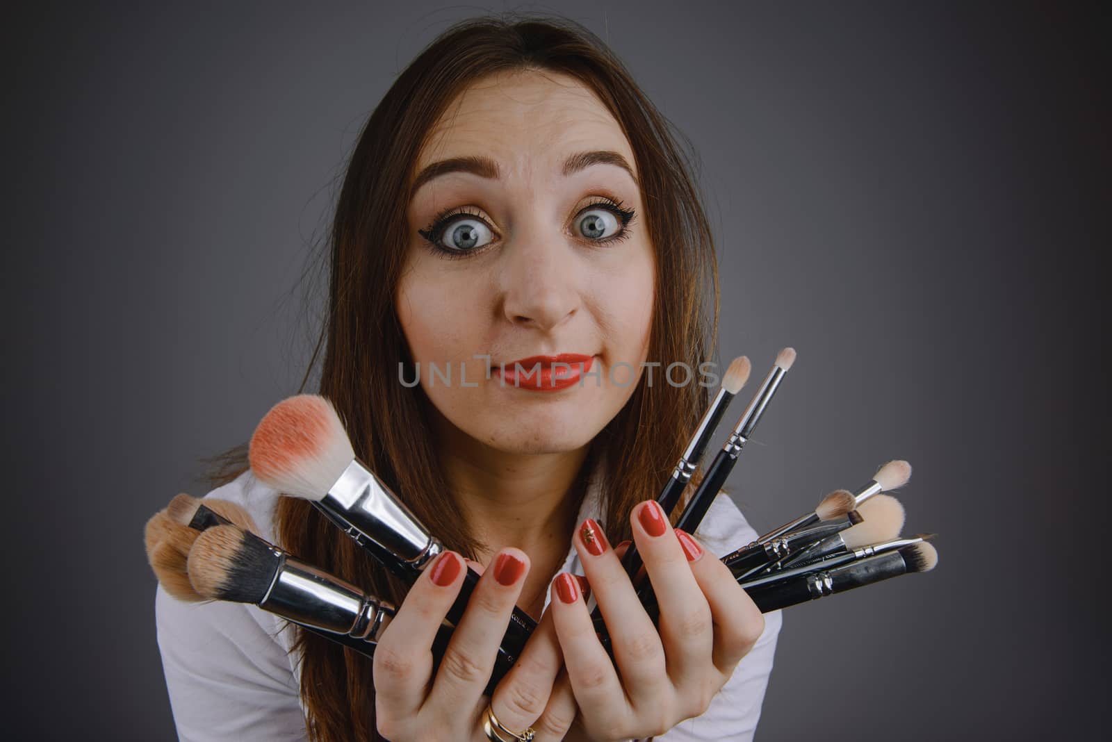 Woman holding a set of cosmetic brushes for make-up, isolated on gray