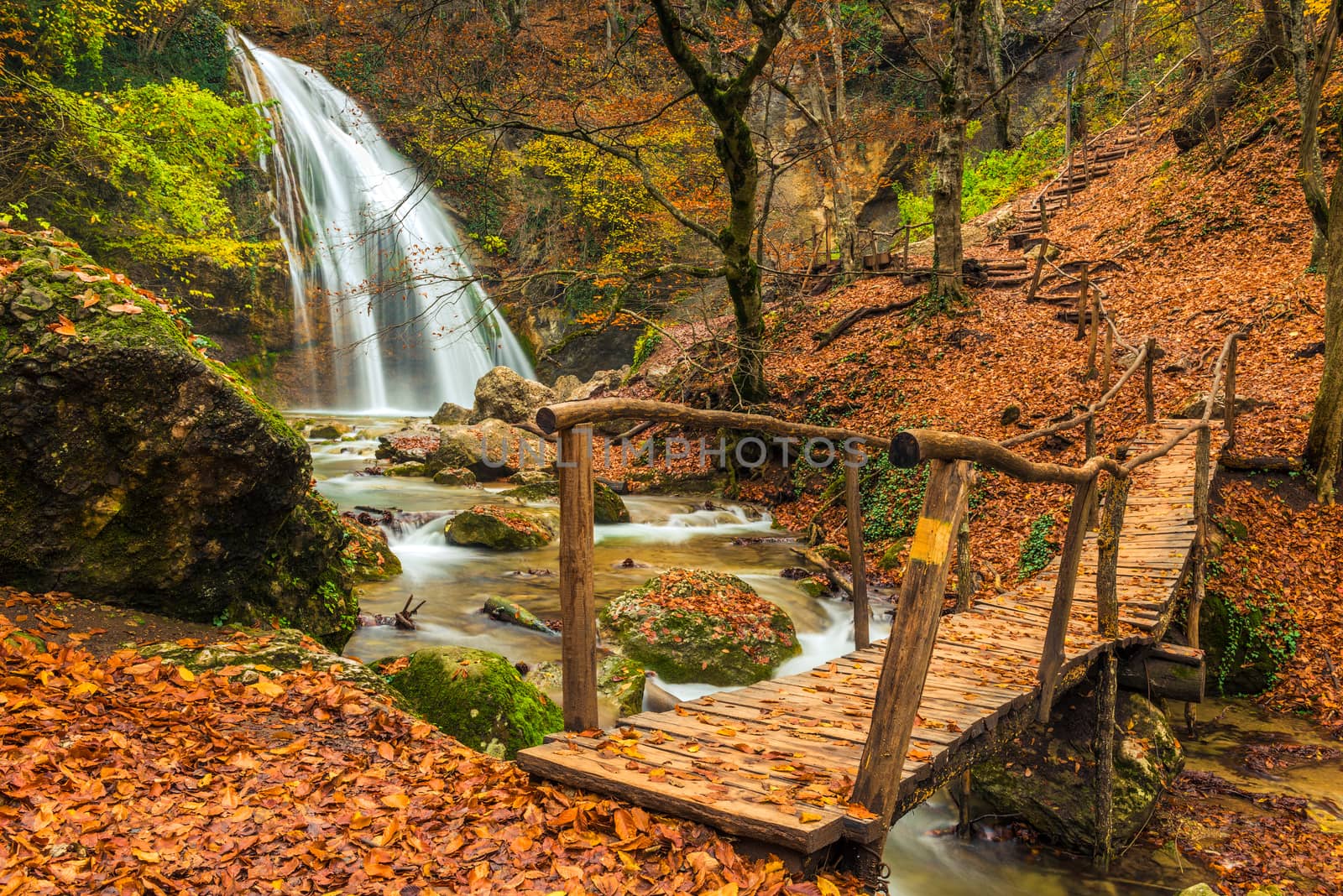 Beautiful view of the picturesque waterfall Jur-Jur and the old wooden bridge, autumn Crimea, Russia