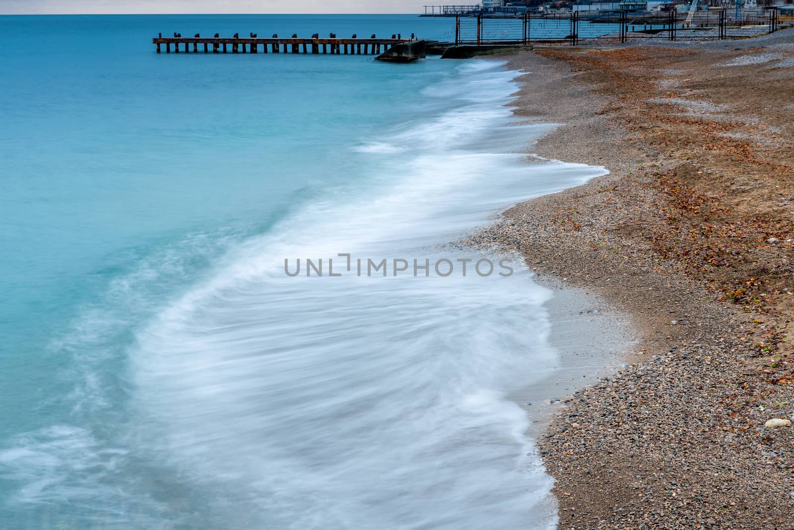 The current sea wave rolls on the beach, autumn gloomy landscape