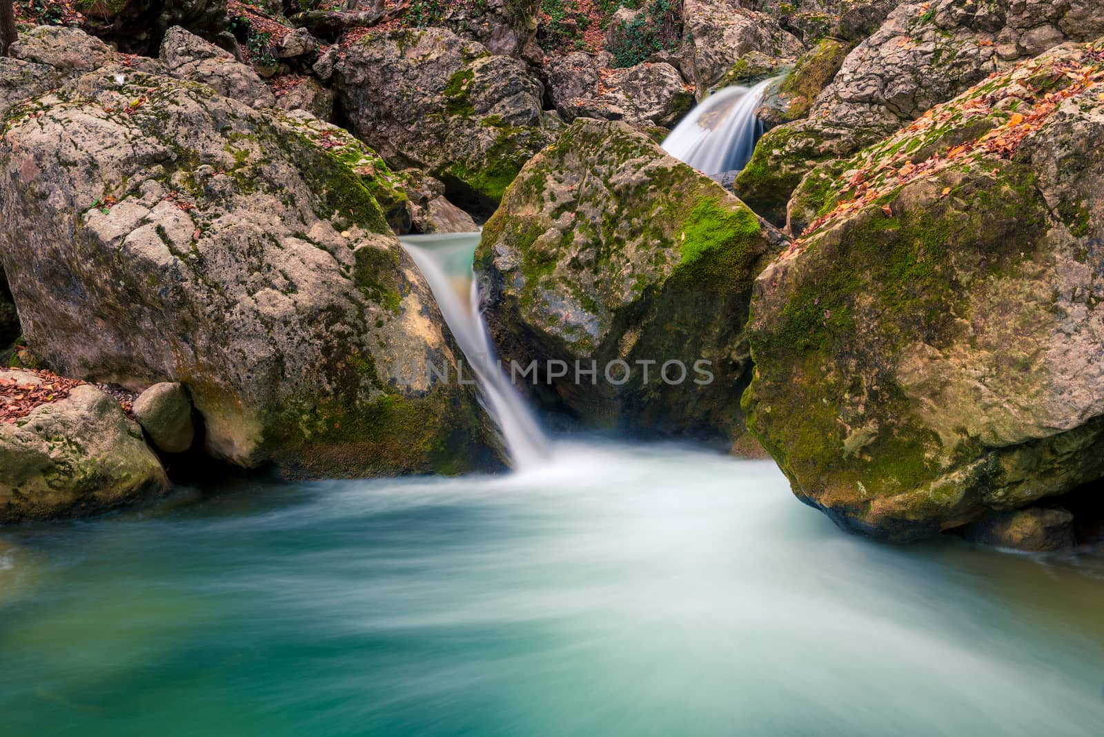 Beautifully flowing water between stones in the mountains, boulders covered with moss, beautiful nature