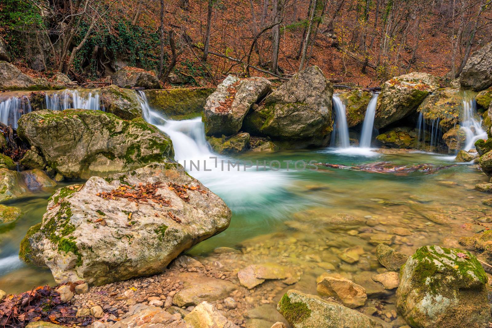 Small waterfalls in a beautiful natural location in the autumn mountain forest