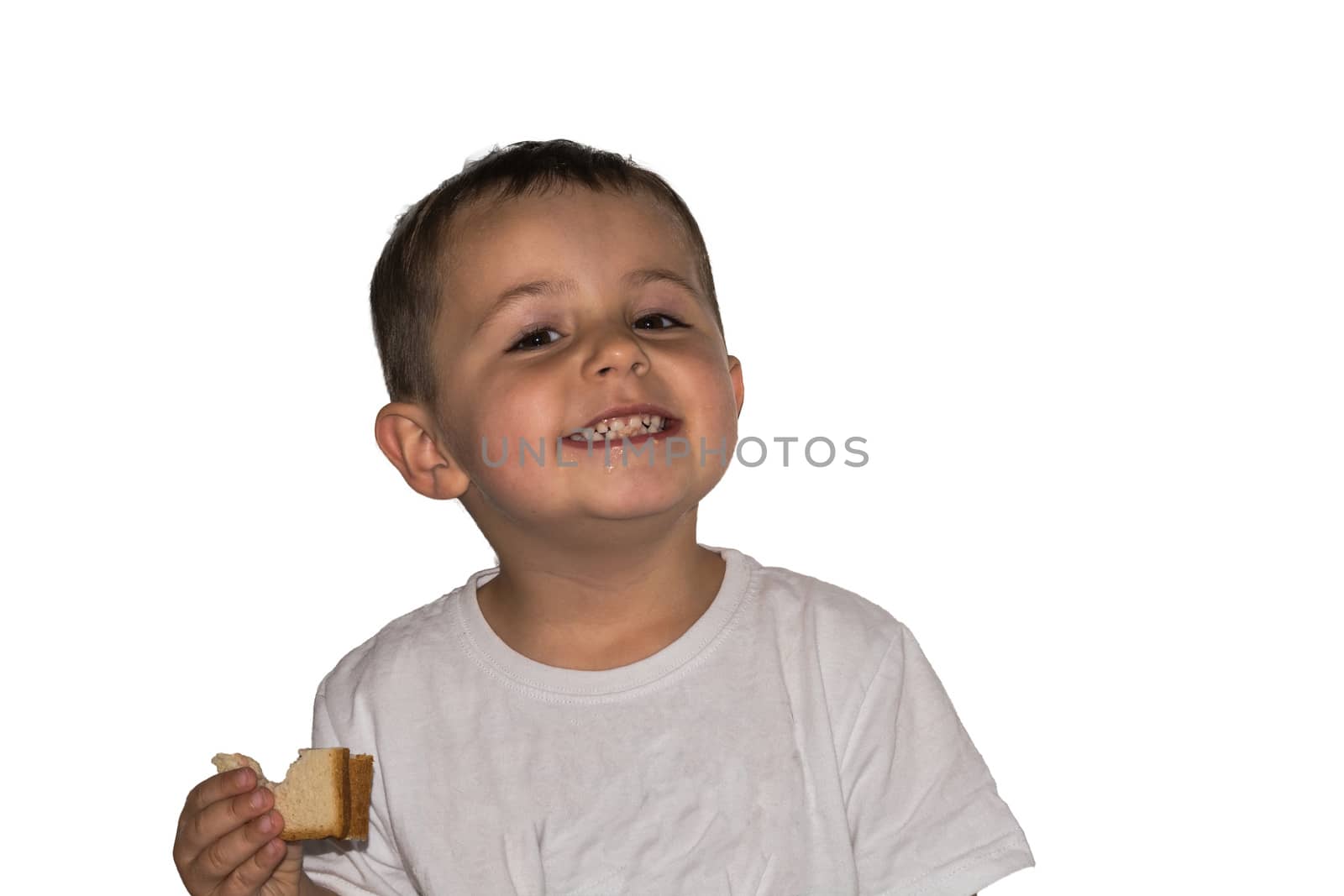 Little laughing boy with toast in hand is standing in front of a white background.