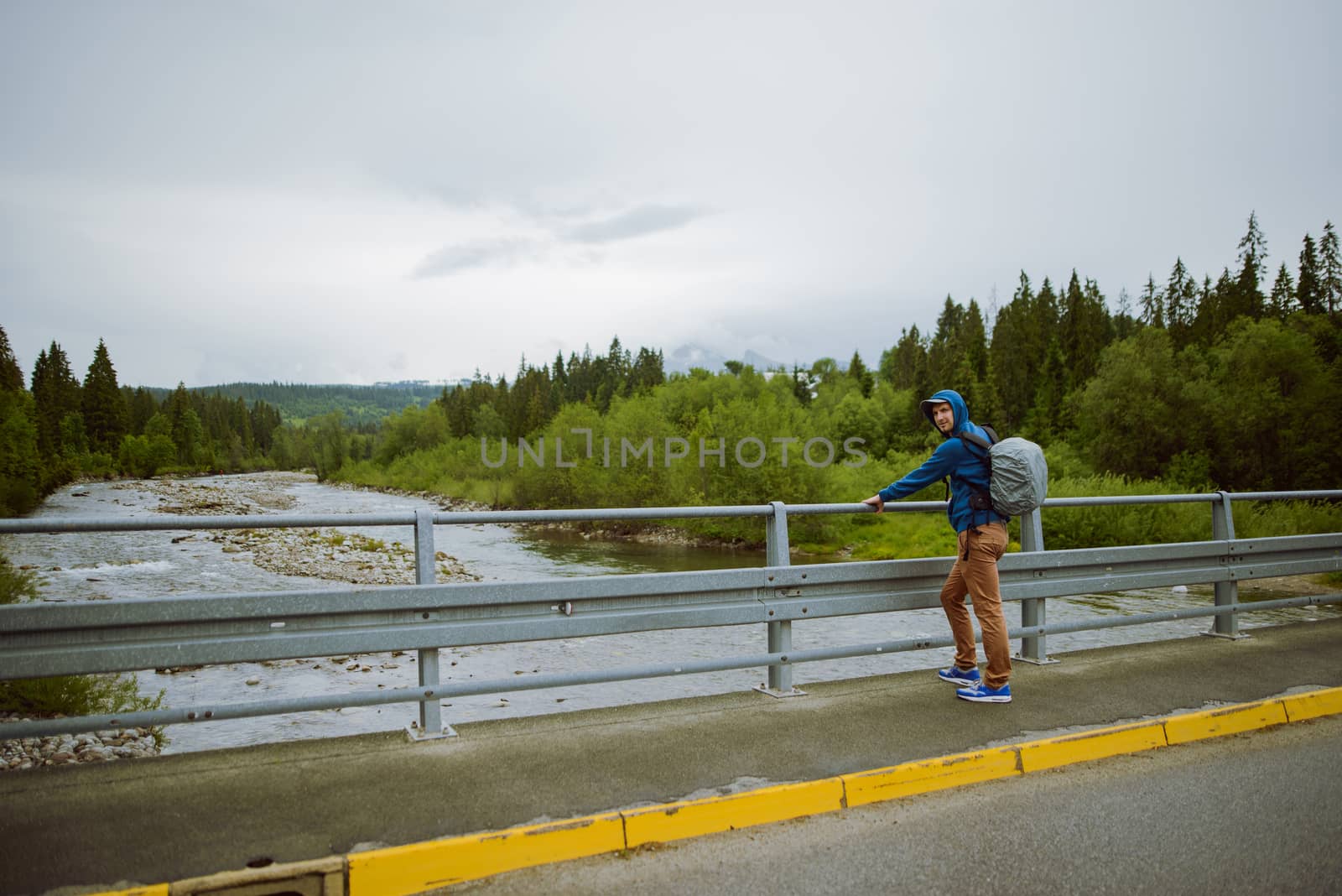 male tourist standing beside the mountain river.