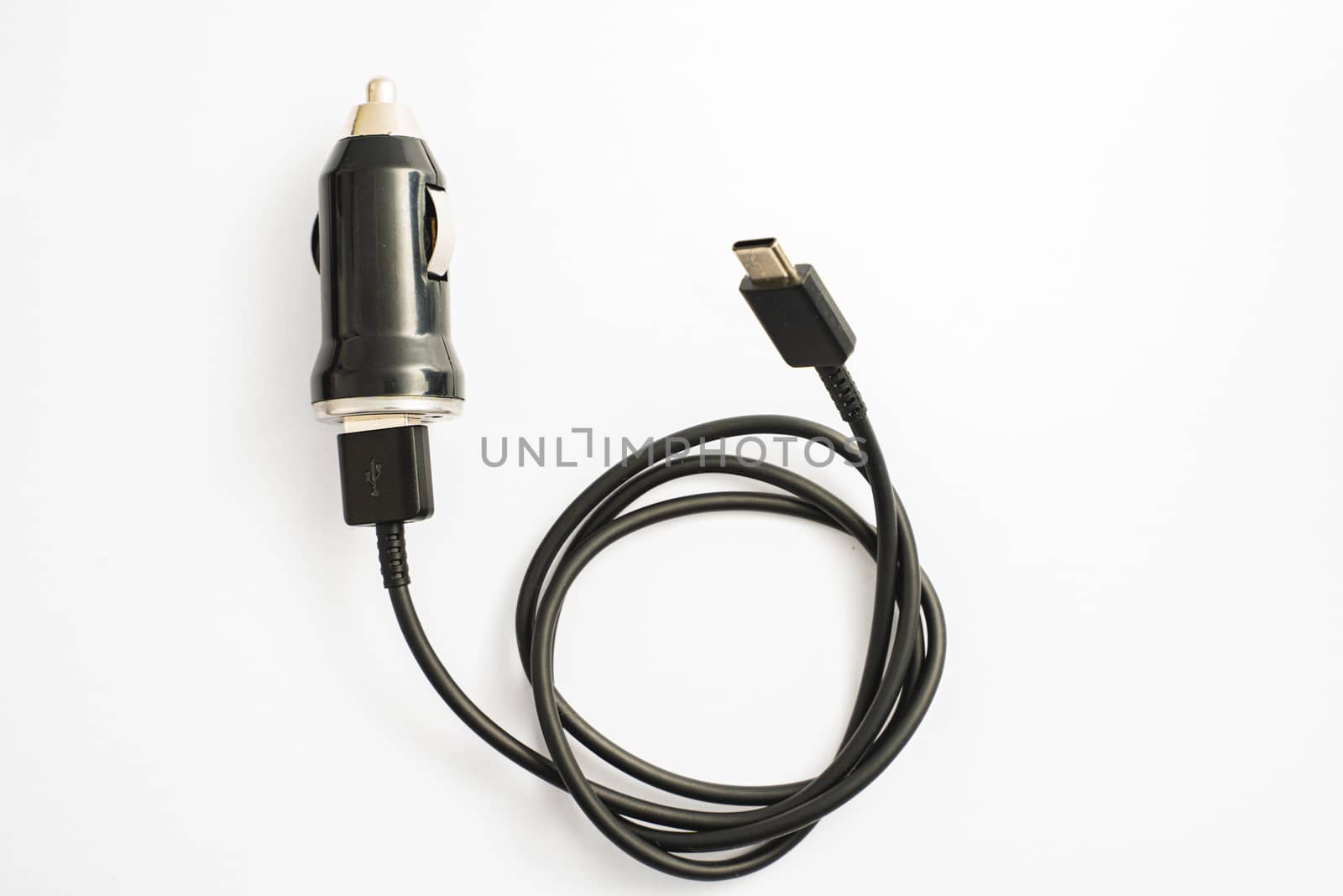 black car charger with USB output connection cable. A photo taken on a black car charger with USB output connection cable against a white backdrop by peerapixs