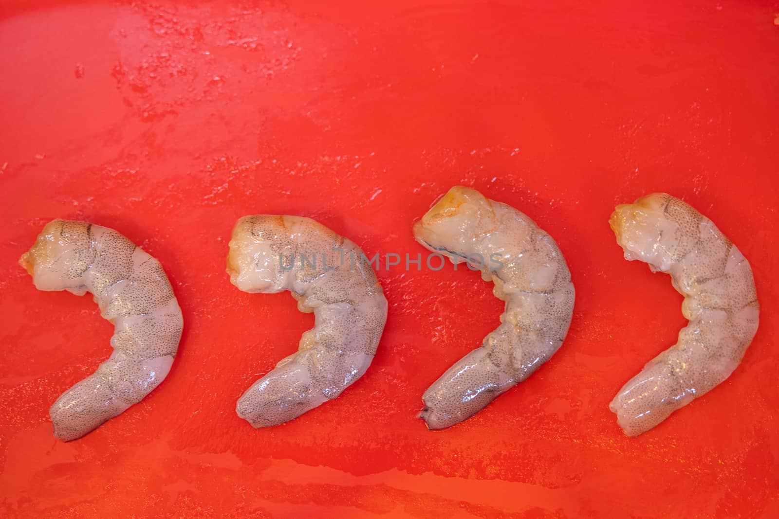 The row Fresh Shrimp in red plate background for cook by peerapixs