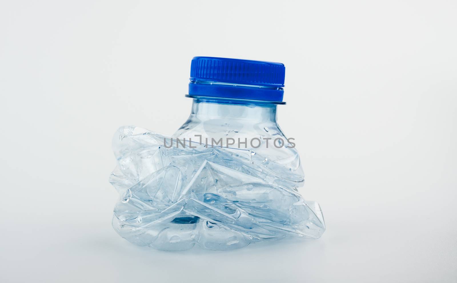 Closeup on empty trash crushed bottle of spring water isolated on white