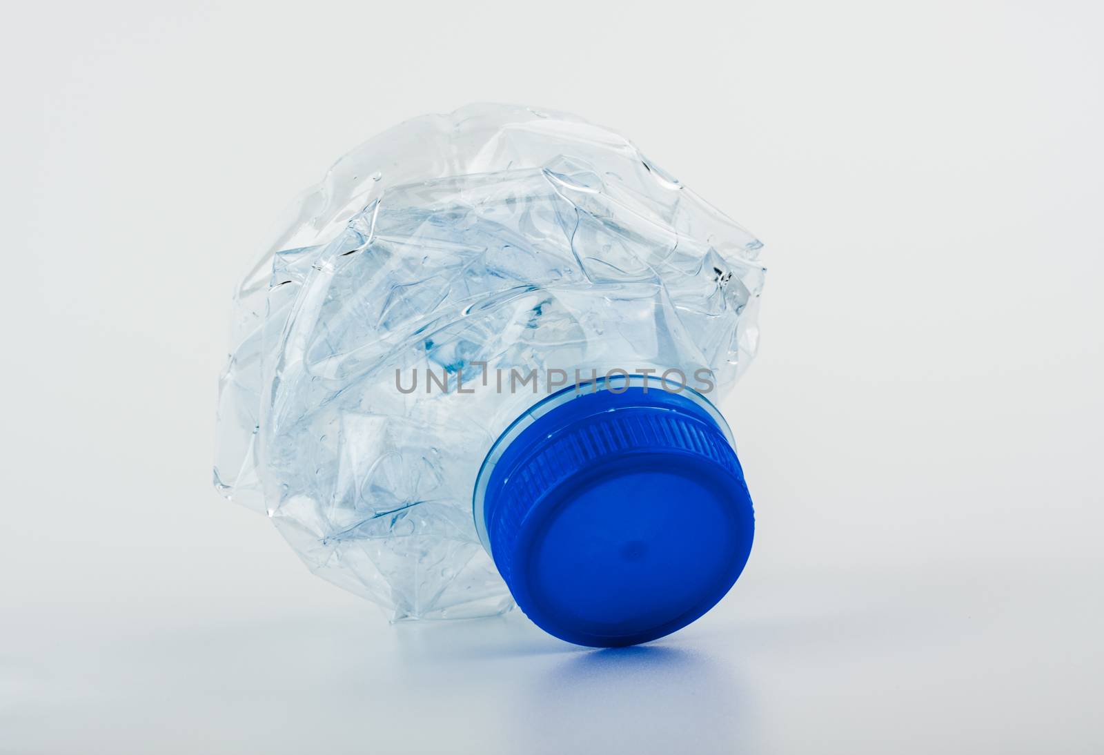 Closeup on empty trash crushed bottle of spring water isolated on white
