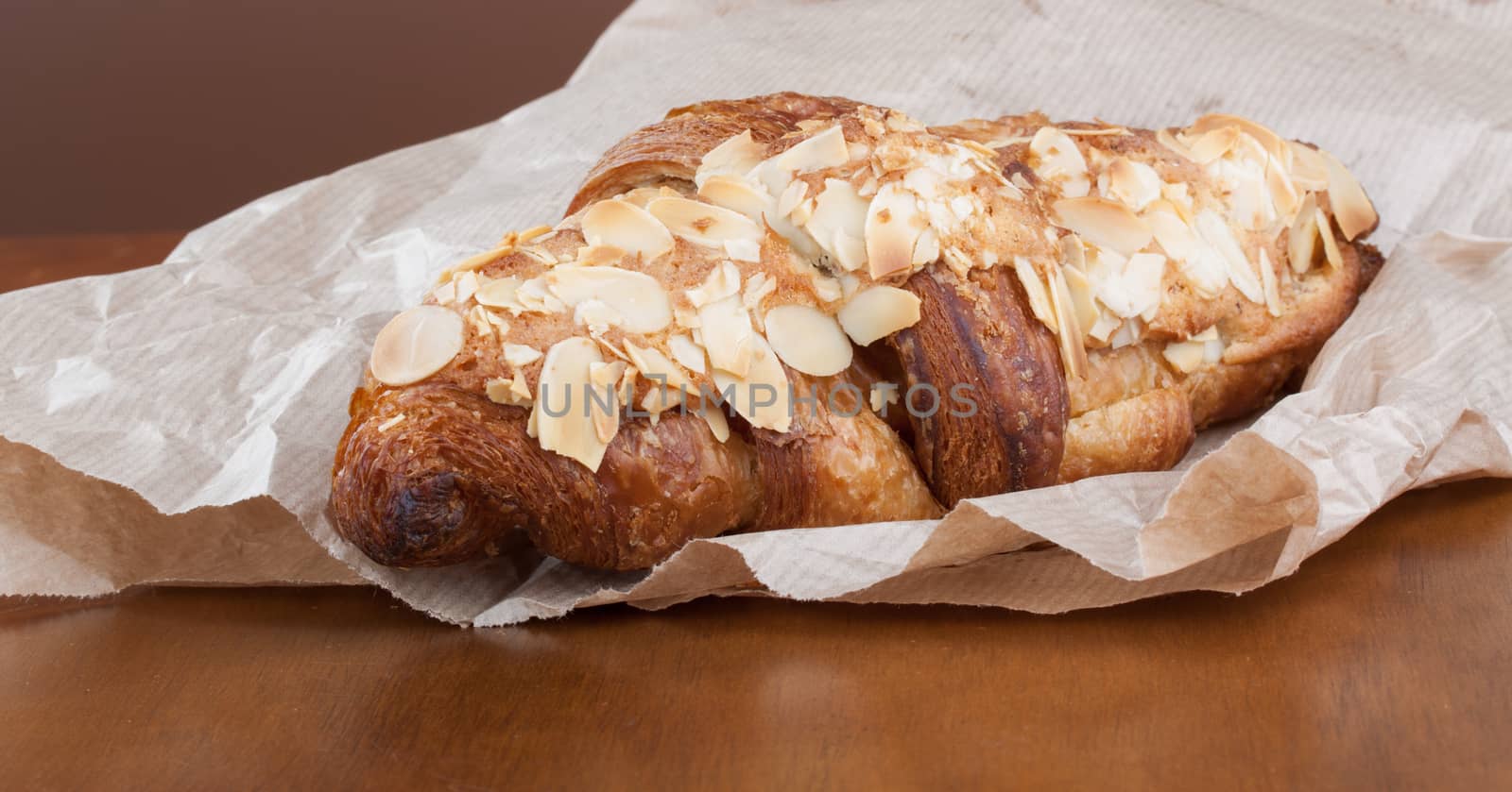 Fresh delicious golden almond crescent in paper bag by lanalanglois