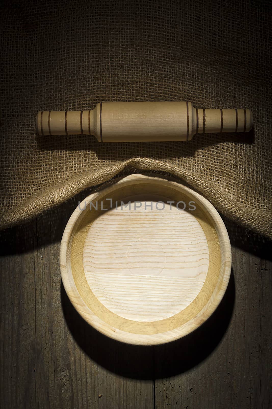 Wooden plate and rolling pin on an old burlap covered table