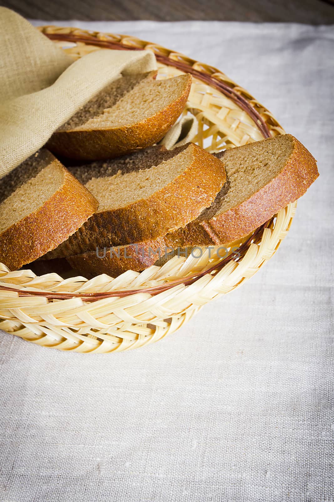 Sliced bread in a basket on a table covered with a linen tablecloth