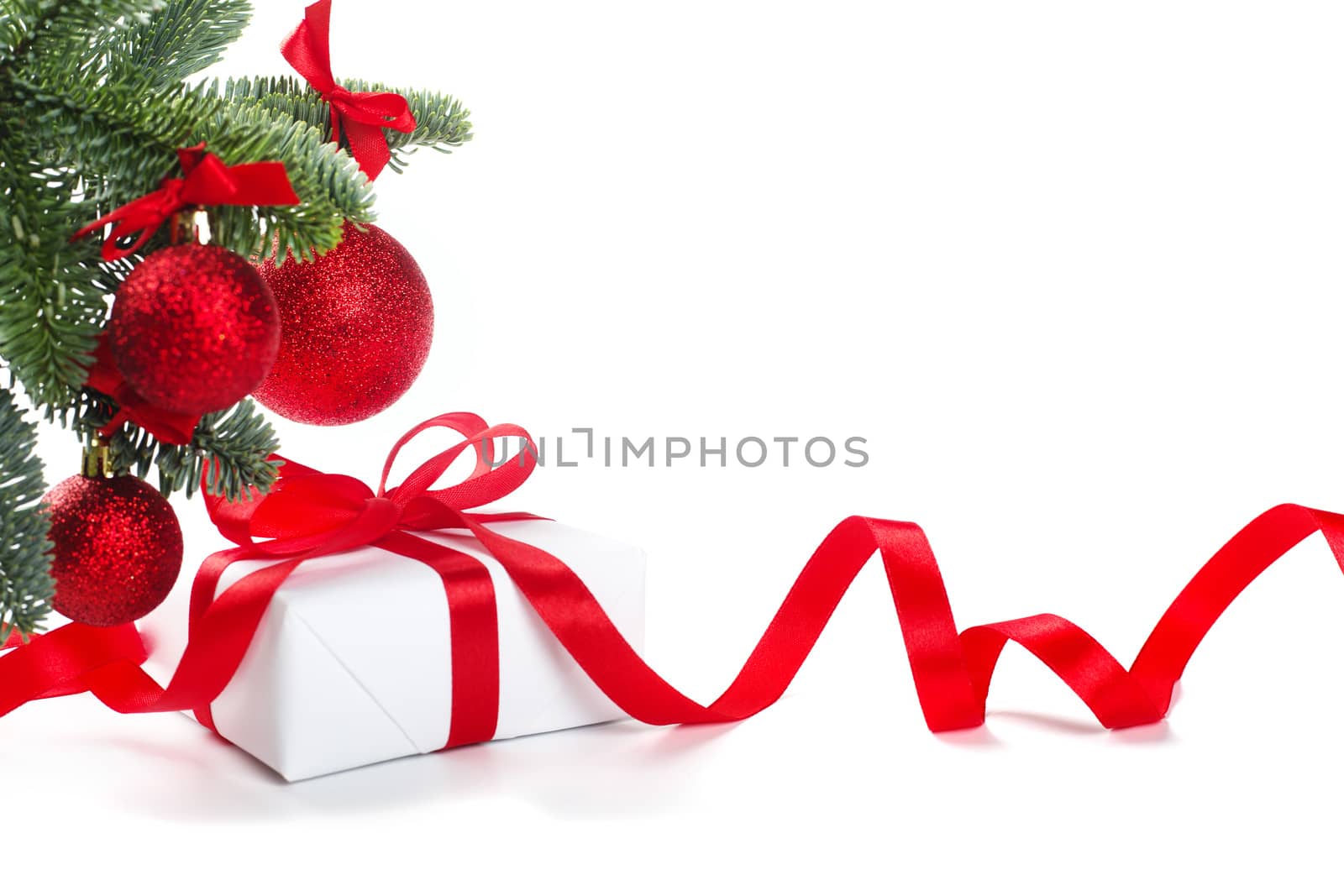 White holiday present gift box with red satin bow and curly ribbon under Christmas tree with baubles, border frame design isolated on white background