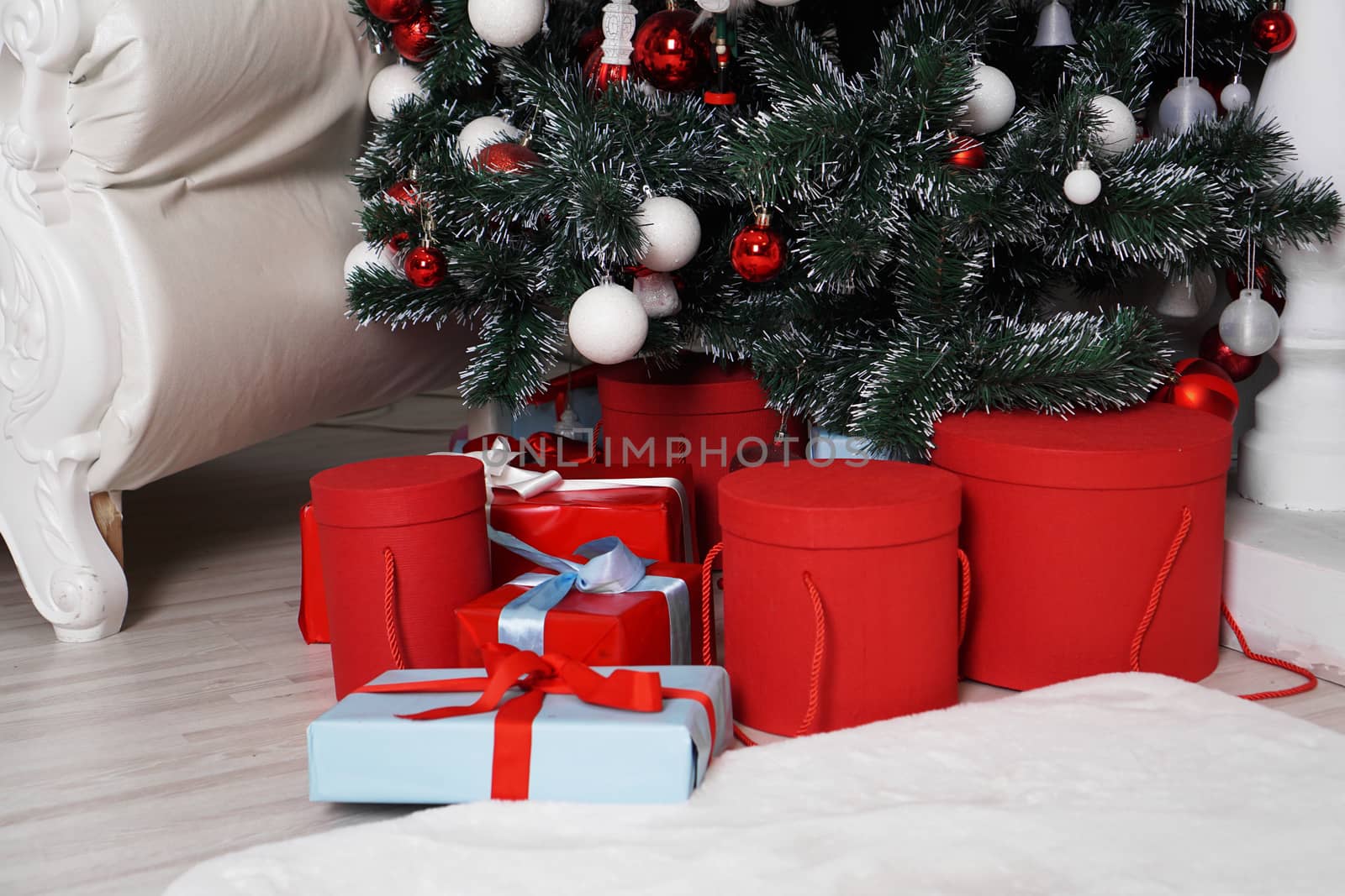 Lots of beautifull wrapped Christmas presents in round boxes in red and blue under the Christmas tree. Concept of Christmas and New Year holidays.